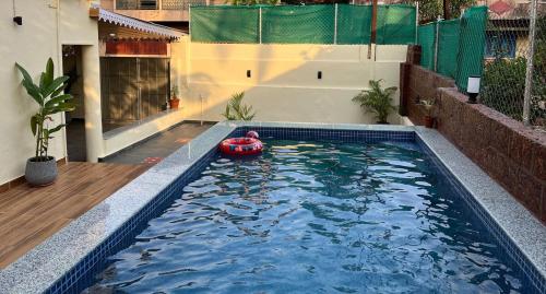 a swimming pool with a red boat in the water at Zuluk Poolside Luxury Homestay with Swimming Pool in Ratnagiri