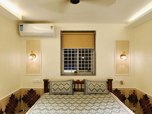 a bedroom with a bed with two pillows and a window at Zuluk Poolside Luxury Homestay with Swimming Pool in Ratnagiri