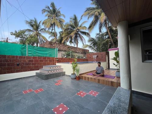a man sitting on a bench in front of a house at Zuluk Poolside Luxury Homestay with Swimming Pool in Ratnagiri