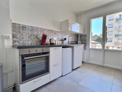 une cuisine avec des appareils blancs et une grande fenêtre dans l'établissement L'artiste - centre ville, à Valence