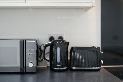 a group of appliances sitting on a counter next to a microwave at Stylish Modern Apartment by Aldgate East Station 2 in London