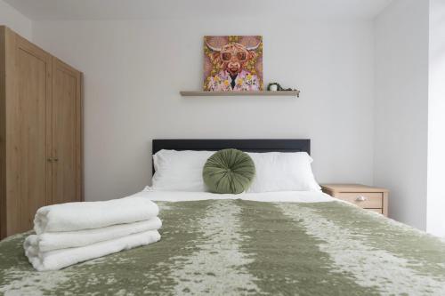 a bedroom with a bed with white sheets and a painting at Stylish Modern Apartment by Aldgate East Station 2 in London