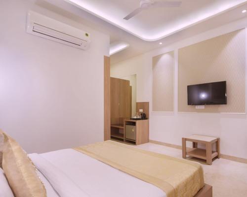 a bedroom with a bed and a tv on the wall at Hotel Star Suites By Star Group in New Delhi