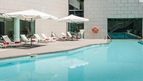a large swimming pool with chairs and umbrellas at Eurostars Reina Felicia in Jaca