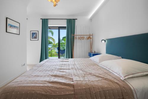 une chambre avec un grand lit et une grande fenêtre dans l'établissement Laminerve Pramousquier, au Lavandou