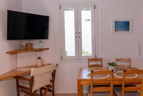 a dining room with a table and a tv at White Holidays Project Ag. Sostis in Agios Sostis