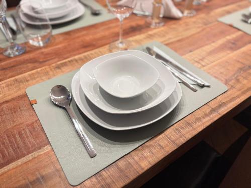 a table with plates and silverware on a wooden table at Bungalow - Kinderspielplatz - Garten mit Feuerstelle in Timelkam