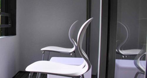 two white chairs sitting in front of a mirror at PLAZA INN stays design Dortmund in Dortmund