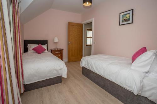 a bedroom with two beds with pink pillows at Garryvoe Beach Homes in Garryvoe