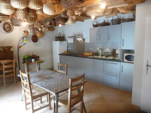 une cuisine avec des armoires blanches et une table et des chaises dans l'établissement chambre d'hôtes Lou Couradou, à Grospierres