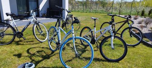 four bikes parked in the grass in front of a house at Biały Dom in Sarbinowo