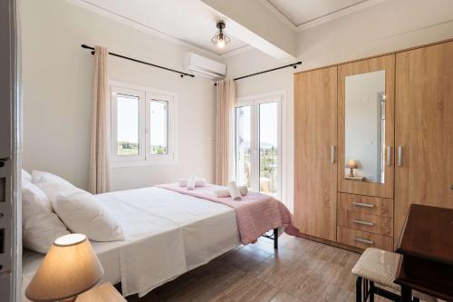 a bedroom with a white bed and a large window at Seaview Tranquility - Elegant Escapes by the Shore in Ayía Kiriakí