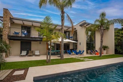 une maison avec une piscine et des palmiers dans l'établissement Laminerve Pramousquier, au Lavandou