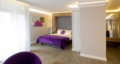 a bedroom with a bed with a purple blanket at PLAZA INN stays design Dortmund in Dortmund