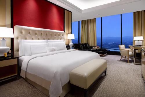 a bedroom with a large bed and a red wall at The Trans Luxury Hotel Bandung in Bandung