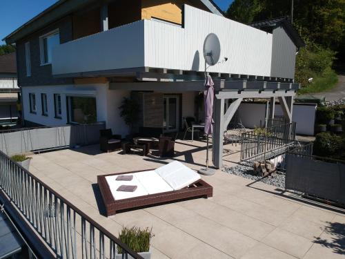 a house with a patio with a table and an umbrella at Seeblick-Ferienwohnung im "Ferienhaus Agger-Blick" mit traumhafter Sonnen-Terrasse, Sauna, E-Kamin & Kajak in Gummersbach