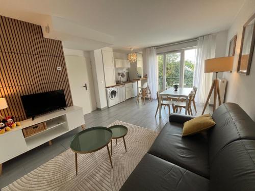 un salon avec un canapé en cuir noir et une table dans l'établissement Disney Dream, à 8 minutes de Disneyland Paris!, à Serris