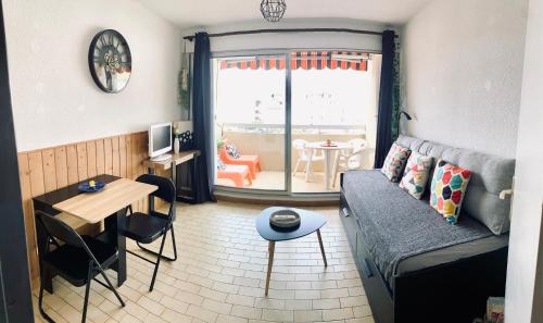un petit salon avec un canapé et une table dans l'établissement charmant studio dans résidence en bord de mer, au Grau-du-Roi