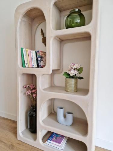 a book shelf in a room with flowers and books at Fully equiped 100 m2 appt with the perfect location in Vilvoorde