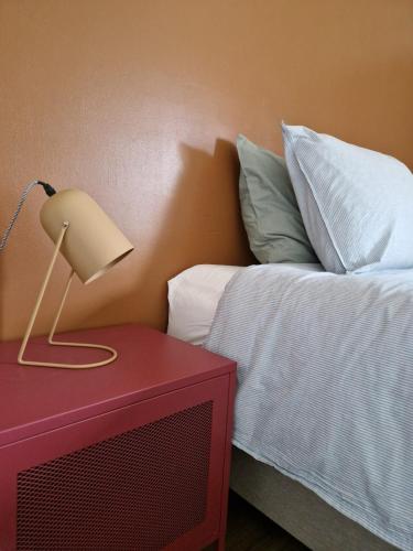 a bed with a red table with a lamp on it at Fully equiped 100 m2 appt with the perfect location in Vilvoorde