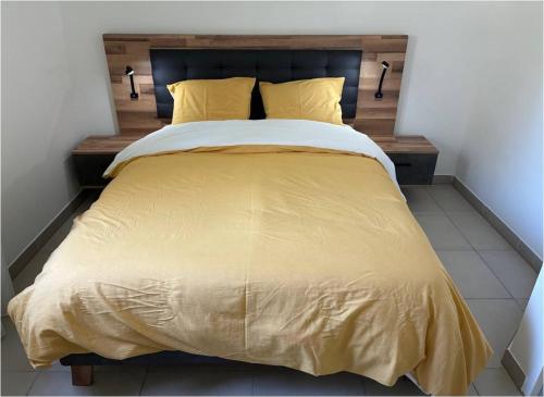 un grand lit avec un couvre-lit jaune et des oreillers jaunes dans l'établissement Appartement neuf et climatisé, 6 personnes, à 150m de la plage, à Vias