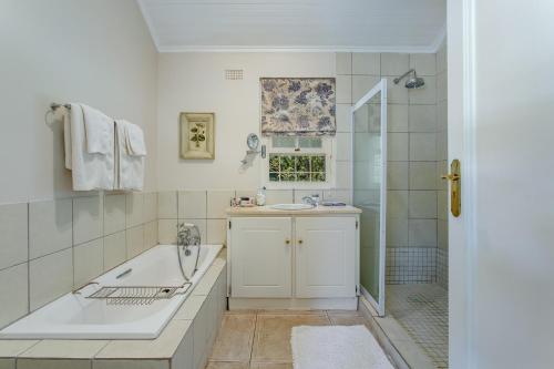 a bathroom with a tub and a sink and a shower at Franschhoek Rose Cottages in Franschhoek