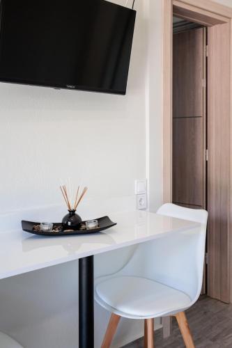 a white table with a white chair and a tv on a wall at Seaview and Sunsets - Beachside Retreats in Ayía Kiriakí