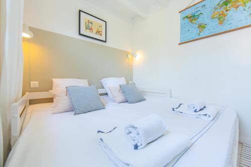 a bedroom with a white bed with blue pillows at Appartement le Capitaine pour 4 personnes in Cap-Ferret