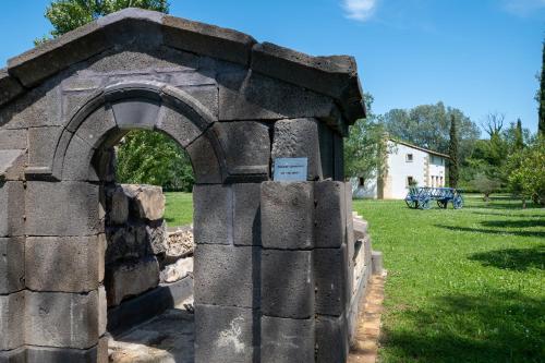un mur en pierre avec une arche dans un parc dans l'établissement Mas des Eaux Claires Arles Camargue, à Saint-Gilles