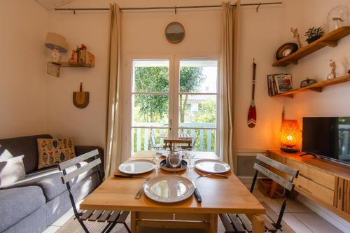 a living room with a table and a couch at Appartement le Capitaine pour 4 personnes in Cap-Ferret