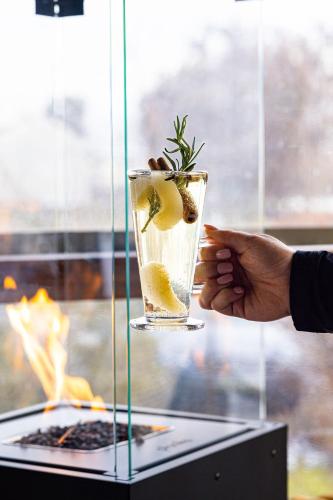 a person holding a drink with a plant in it at Ranczo w Dolinie in Dobre Miasto