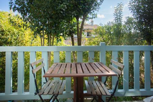 a wooden table and chair on a white fence at Appartement le Capitaine pour 4 personnes in Cap-Ferret