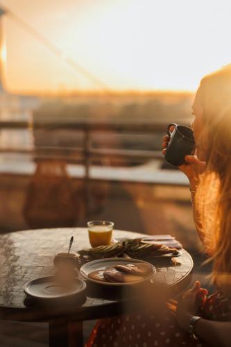 a woman sitting at a table drinking a cup of coffee at Hotel Indigo Bordeaux Centre Chartrons by IHG in Bordeaux