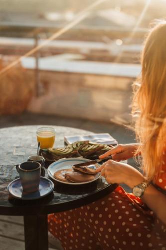 a woman sitting at a table with a plate of food at Hotel Indigo Bordeaux Centre Chartrons by IHG in Bordeaux