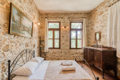 a bedroom with a bed and a dresser and windows at Medieval Villa Philoxenia in Kalamoti