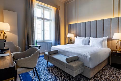 a hotel room with a large bed and a chair at Grandhotel Pupp in Karlovy Vary