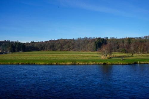 a large body of water with a field and trees at West Lodge, High Street in Aberlour