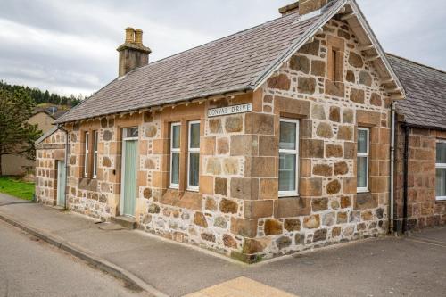an old stone building on the side of a street at West Lodge, High Street in Aberlour
