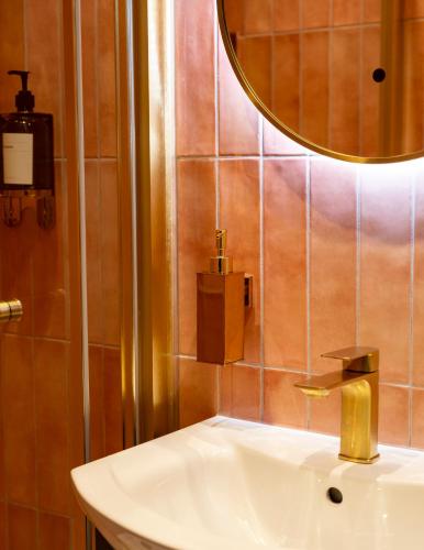 a bathroom sink with a gold faucet and a mirror at The Woodquay Townhouse in Galway
