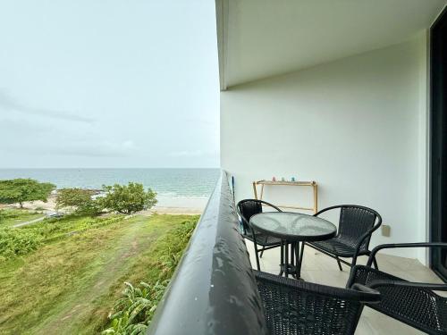 a balcony with a table and chairs and the ocean at Escape Condominiums Beachfront Suites - Mae Phim in Rayong