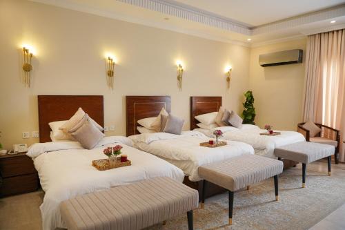 a hotel room with three beds and two chairs at Alhamra Hotel in Mardan