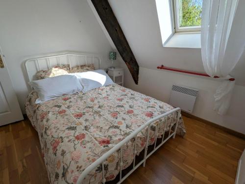 - une chambre avec un lit doté d'un couvre-lit floral et d'une fenêtre dans l'établissement Maison historique avec jardin secret à Limerzel, à Limerzel