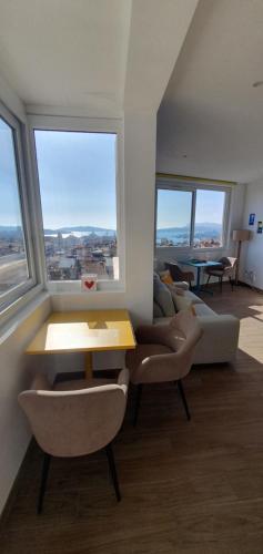 un salon avec une table, des chaises et des fenêtres dans l'établissement Panoramic Sea View, Walk to Train Station and Port - Vue Mer Panoramique, Gare et Port à Pied, à Toulon