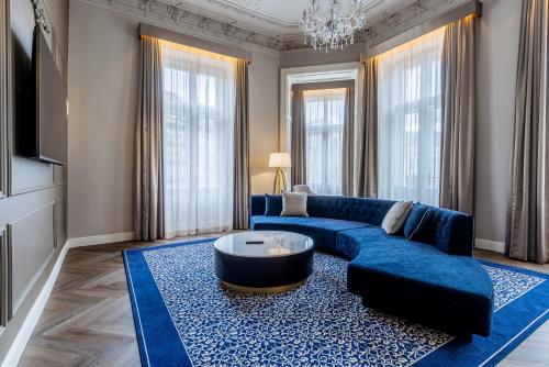 a living room with a blue couch and a table at Grandhotel Pupp in Karlovy Vary