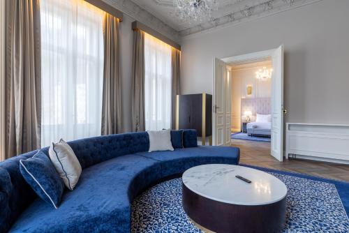 a living room with a blue couch and a table at Grandhotel Pupp in Karlovy Vary