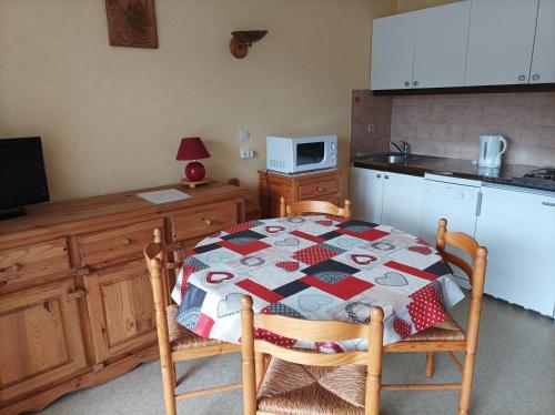 a kitchen with a table with a quilt on it at Studio-cabine Résidence les Rennes in Prémanon