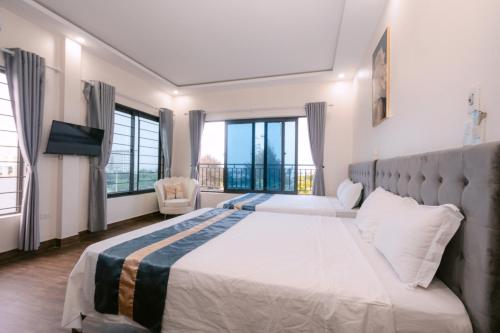a bedroom with a large bed and large windows at Khách Sạn Cát Cát - Hải Tiến in Trung Ngoai