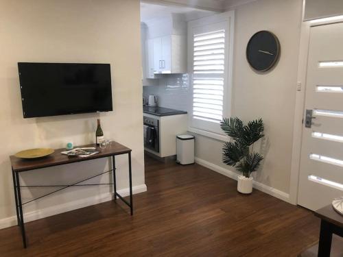 a living room with a table and a television on a wall at Perfection On Prince in Orange