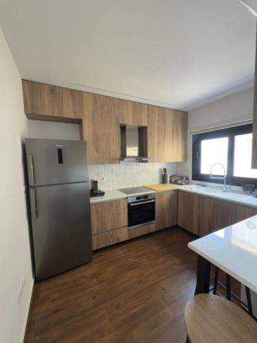 a kitchen with a stainless steel refrigerator and wooden cabinets at Stylish 2 bedroom apartment in Limassol in Limassol