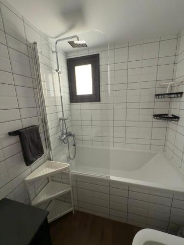 a white tiled bathroom with a tub and a window at Stylish 2 bedroom apartment in Limassol in Limassol